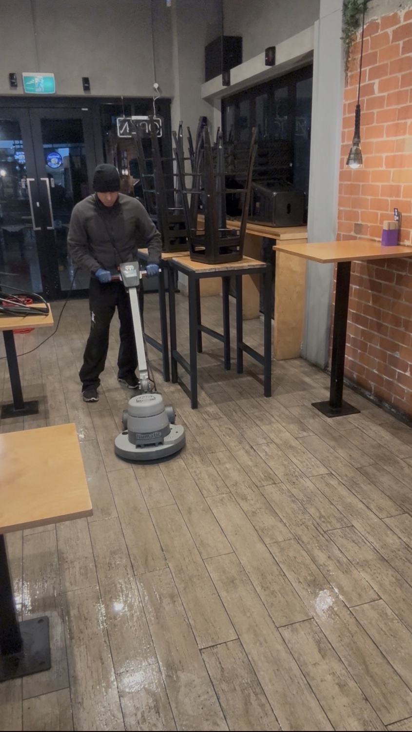 UrbanShine cleaner operating a commercial floor machine at a real Auckland hospitality site