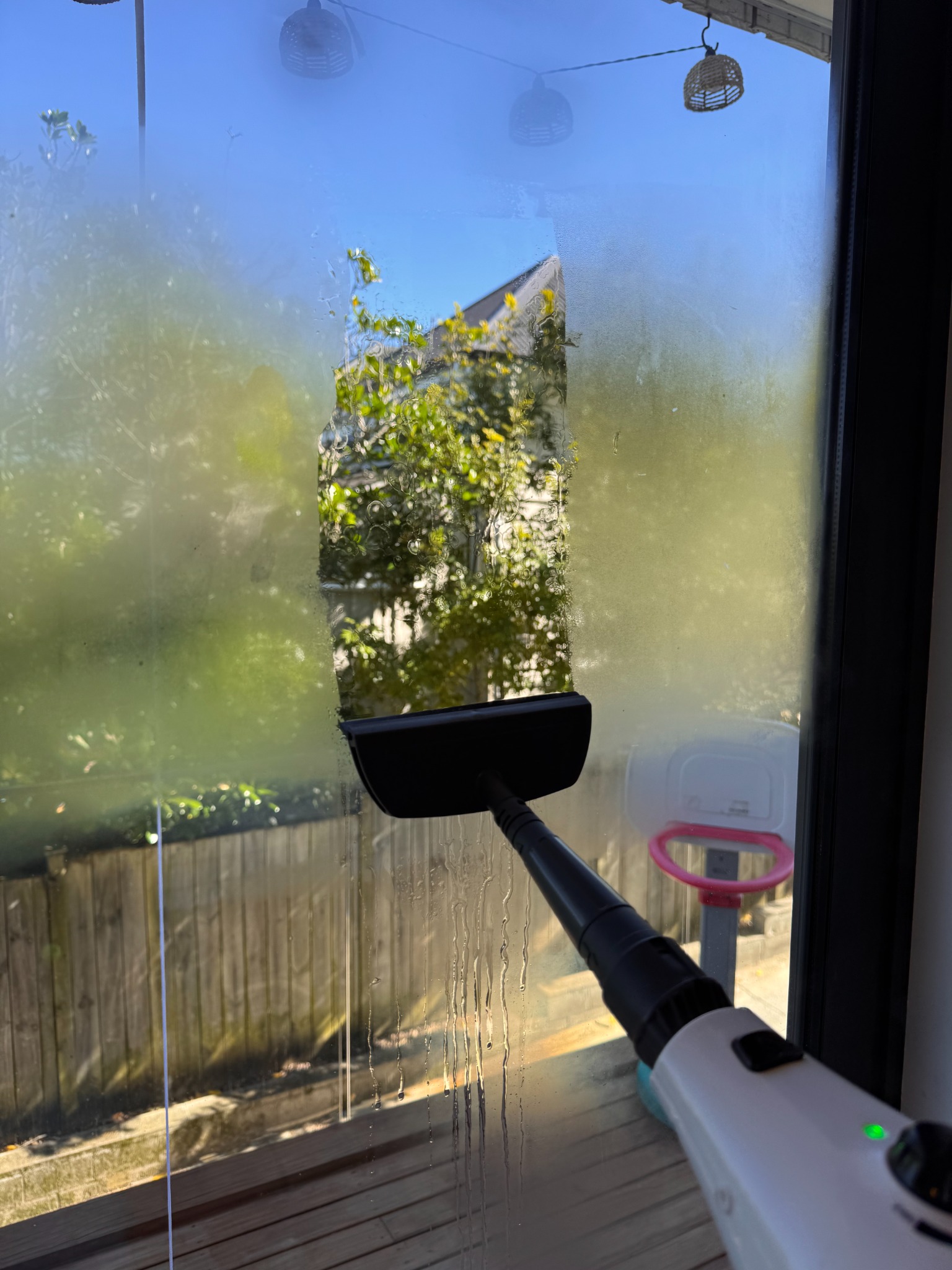 Close-up of UrbanShine steam cleaning window glass on a real residential job