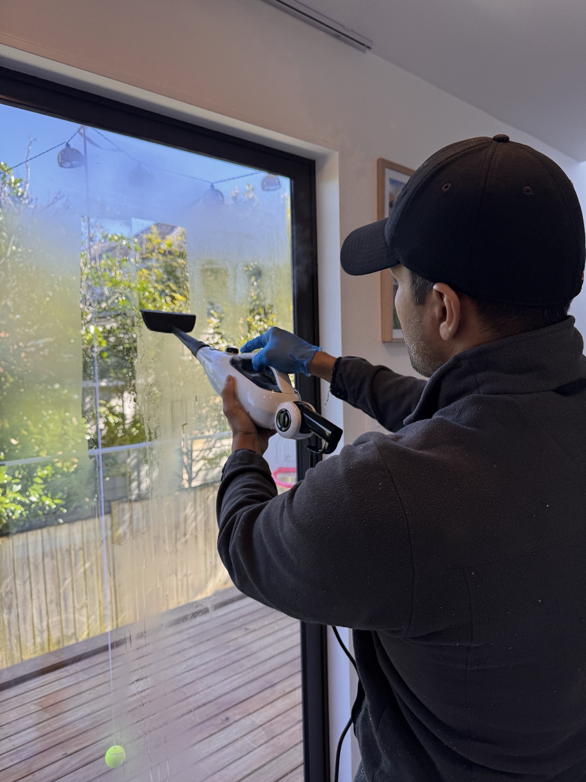 UrbanShine team member steam cleaning window glass at a real Auckland residential job